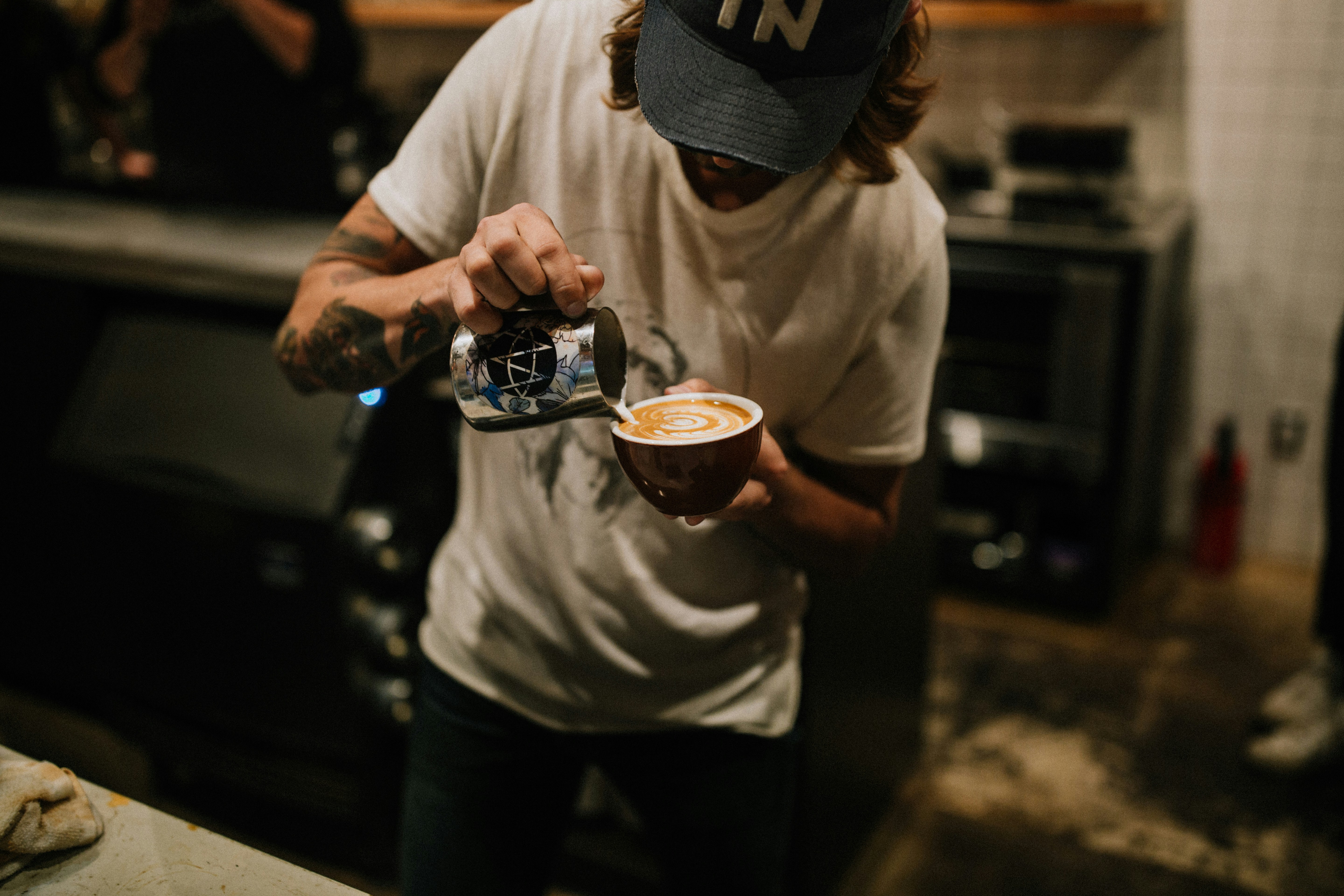 Barista sirviendo leche texturizada sobre un latte